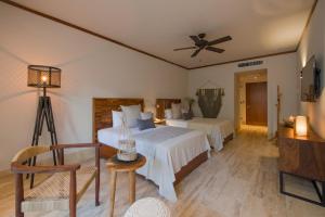 a hotel room with a bed, chair, and table at Kimpton Aluna Resort Tulum, an IHG Hotel in Tulum