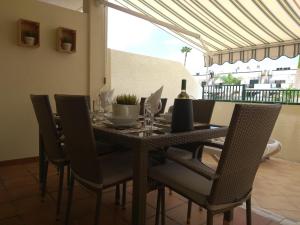 een eettafel met stoelen en een fles wijn bij Residencial Los Geranios 13 in Costa Del Silencio