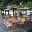 a wooden table and chairs with an umbrella at Hôtel La Tour D'Auvergne in Pont-lʼAbbé