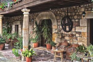 un patio extérieur avec des plantes, des tables et un mur en pierre dans l'établissement Casa Velarde, à Torrelavega