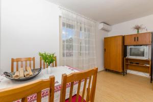 ein Esszimmer mit einem Tisch mit Stühlen und einem TV in der Unterkunft Apartment Maslina in Vodice