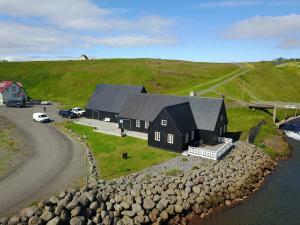 a black house on a hill next to a road at Fraendgardur in Hofsós