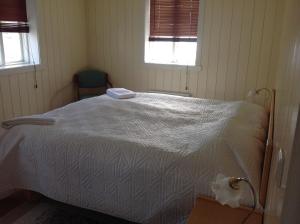 1 dormitorio con 1 cama blanca y 2 ventanas en Fraendgardur, en Hofsós