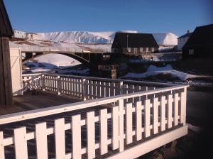 un pont sur une rivière avec une montagne enneigée dans l'établissement Fraendgardur, à Hofsós