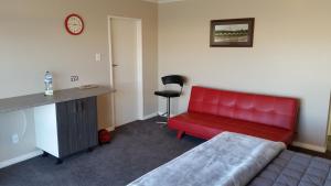 a red couch in a room with a desk at Moeraki Boulders Motel in Hampden