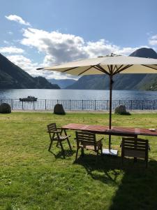 a picnic table with an umbrella next to a lake at Sogn Hotel in Vadheim