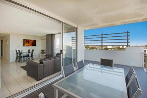 un soggiorno con tavolo e sedie in vetro di The Chermside Apartments a Brisbane