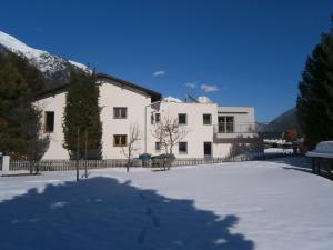 um edifício branco com neve no chão em Appartement Christopherus em Pettneu am Arlberg