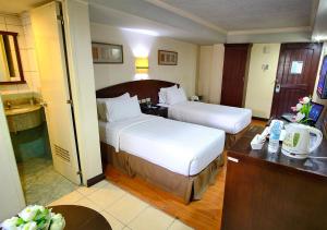 a hotel room with two beds and a bathroom at Fersal Hotel - Manila in Manila