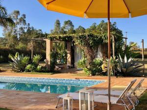 a pool with a yellow umbrella and chairs and a table with an umbrella at Brotas Lodge in Brotas