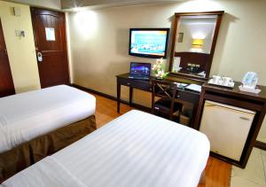 a hotel room with two beds and a desk and a television at Fersal Hotel - Manila in Manila