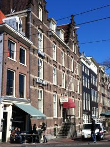 un gran edificio de ladrillo con gente sentada fuera de él en OZO Hotels Armada Amsterdam, en Ámsterdam