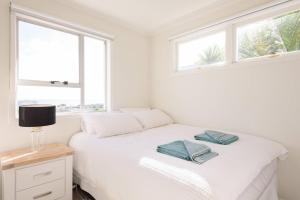 1 dormitorio con 1 cama blanca y 2 toallas en Luxury house with Clifftop Seaview en Whangaparaoa