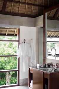 a white robe hanging on a wall in a bathroom at REVĪVŌ Wellness Resort Nusa Dua Bali in Nusa Dua