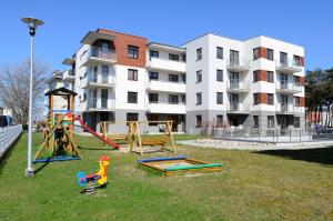 un parque infantil frente a un edificio de apartamentos en Apartamenty Sun & Snow Bursztynowy, en Władysławowo