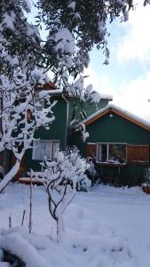 dom z pokrytym śniegiem drzewem przed nim w obiekcie Colibrí House w mieście San Martín de los Andes