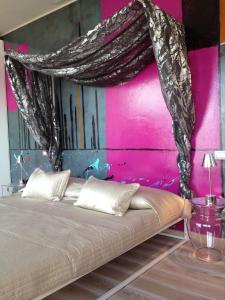 Cama en habitación con pared de color rosa en Hotel Baia dei Pini, en Torri del Benaco
