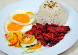 einen Teller mit Lebensmitteln mit Eiern, Fleisch und Reis in der Unterkunft Fersal Hotel Kalayaan, Quezon City in Manila