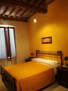 a bedroom with a bed with yellow walls and a window at Nonna Anna in Siena