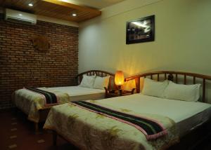 una habitación de hotel con 2 camas y una lámpara en Khách Sạn Xanh hotel, en Kon Tum (2)