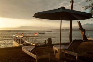 a couple of chairs and an umbrella on a beach at Blue Marine Resort in Gili Air