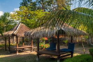 a hut with two chairs and a table and a straw umbrella at Blue Marine Resort in Gili Air