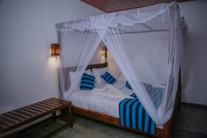 a bedroom with a canopy bed with blue and white pillows at Hotel City Grand Ella in Ella