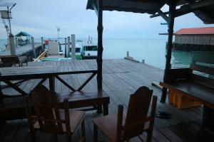 a wooden dock with tables and chairs on the water at Homestay Tanjung Duata Bohe Silian in Maratua Atoll