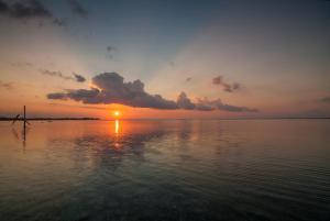 a sunset over a body of water with a sail boat at Blue Marine Resort in Gili Air