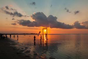 a group of people playing on the beach at sunset at Blue Marine Resort in Gili Air