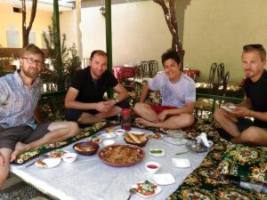 un grupo de hombres sentados alrededor de una mesa con comida en City Hostel Dushanbe en Dusambé