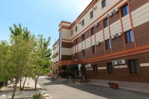 ein großes Gebäude mit einem Baum davor in der Unterkunft Infinity Plaza Hotel in Atyrau