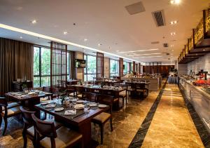 武夷山市にあるFliport Garden Hotel Wuyishanの木製のテーブルと椅子のあるレストラン、バー