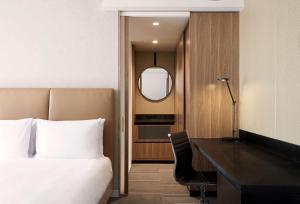 墨尔本Hyatt Place Melbourne Essendon Fields的卧室里有一张床、一张书桌和一面镜子