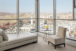 un letto e una sedia in una stanza con finestre di Jabal Omar Hyatt Regency Makkah a La Mecca