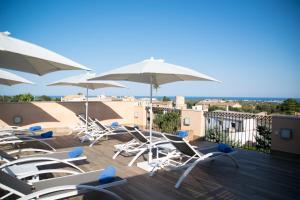 Boutique Hotel Petit Sant Miquel في Calonge: مجموعة من الكراسي والمظلات على السطح