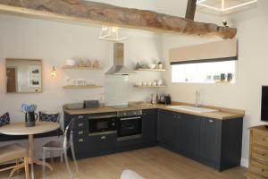 una cocina con armarios negros, fregadero y mesa en The Cottage at The Dene en Chichester