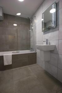 a bathroom with a sink and a tub and a mirror at Beausite Hotel in Grouville