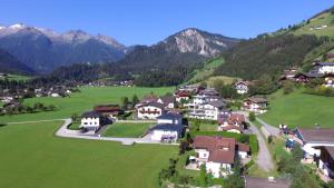a village in a green field with mountains in the background at Appartement Knapp in Wald im Pinzgau