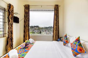 a bedroom with a bed and a window with a view at FabExpress Grand Castle Hill Resorts Ooty Boat House in Ooty