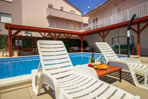 eine Terrasse mit Stühlen und einem Tisch neben einem Pool in der Unterkunft Villa Ljetni San in Omiš