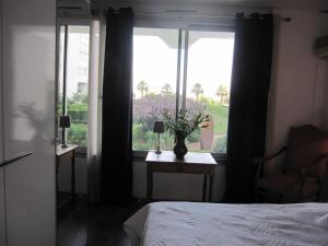 a bedroom with a bed and a window with a vase of flowers at APPARTEMENT DUPLEX 71 m2 - 4 personnes in La Grande Motte