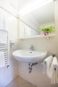 a white bathroom with a sink and a mirror at Pension Lichtenburg in Nalles