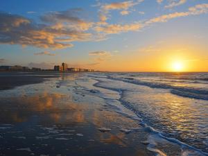 a beach with the sun setting in the distance at Hotel Rubens in Ostend