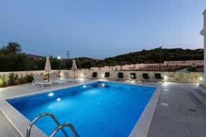 a large swimming pool with chairs at Eudora Luxury Stone Villa in Almyrida