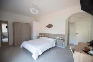 una camera con letto bianco, tavolo e scrivania di La Conchiglia sul Mare a San Felice Circeo