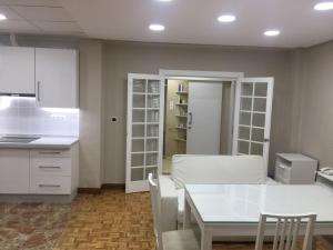 a kitchen with white cabinets and a white table at Apartments soho, Malaga center in Málaga