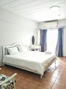 a bedroom with a large white bed and a window at Lomsabai Apartments in Bangsaen