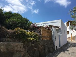 a white building with flowers on a stone wall at Villa in Panarea - Nespolo in Panarea