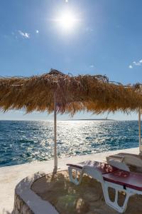 a table and chairs under a straw umbrella on the beach at Holiday Park Mandrice in Mandre